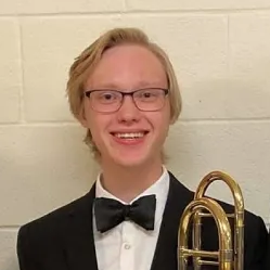 Photo of John Ruediger holding a trombone.