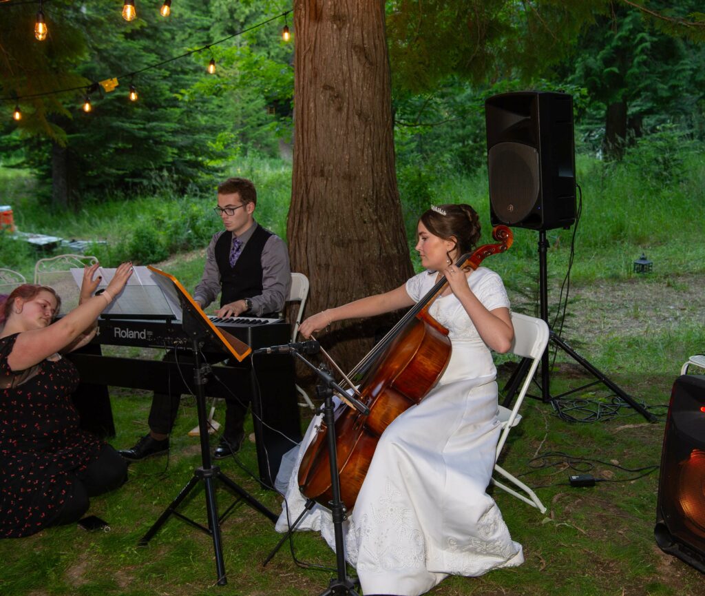 Anyssa playing the cello in the woods as part of a small ensemble.